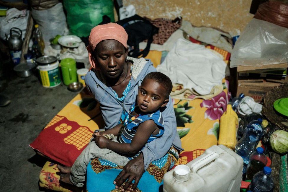 Мать, спасавшаяся от насилия в районе Тыграй в Эфиопии, держит своего ребенка в классе.