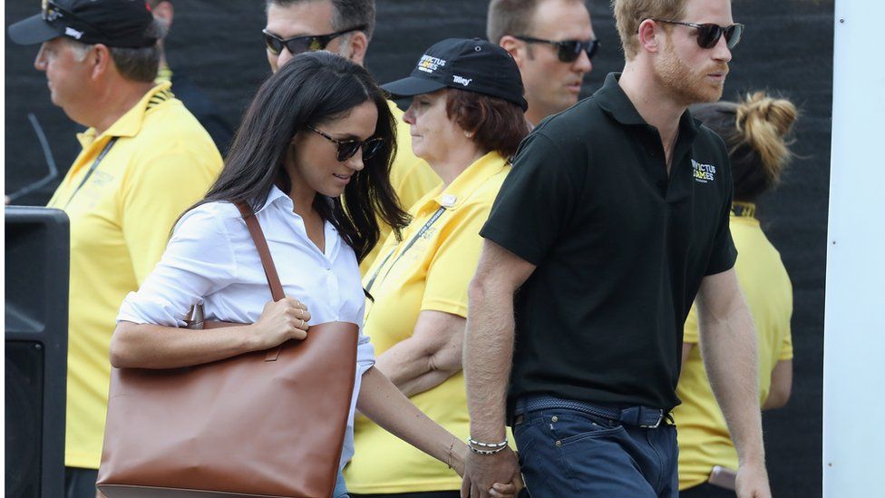 Meghan Markle and Prince Harry hold hands during their first public appearance as a couple