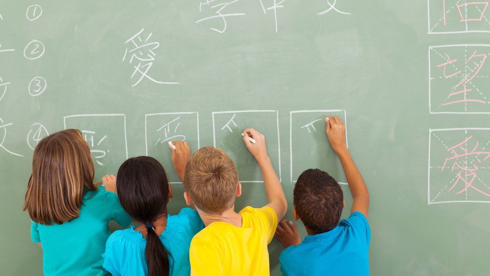 Children writing Chinese on a blackboard