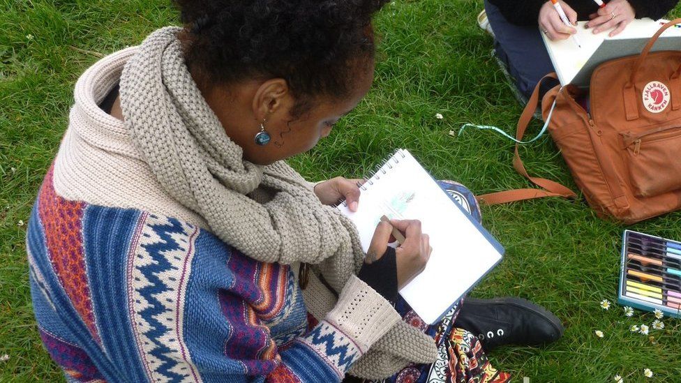 Jasmine Ibrahim sits drawing in a pad