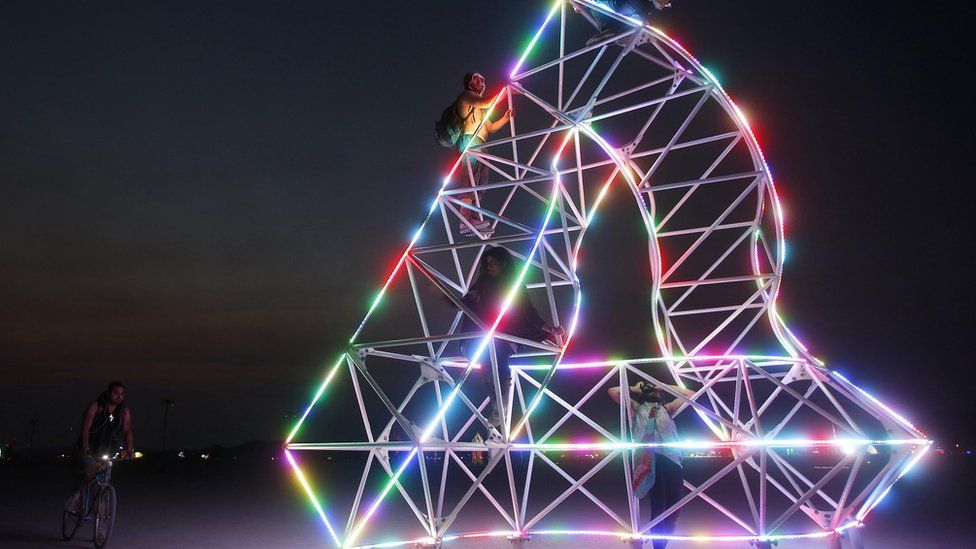 Festival goers climb an art installation at Burning Man 2013