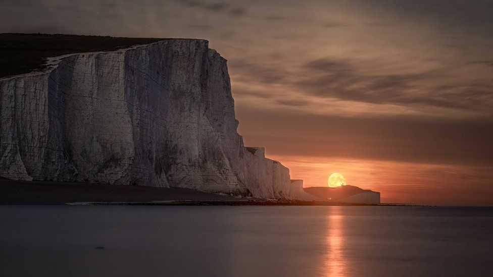 The moon rises above the sea and next to the Seven Sisters cliffs