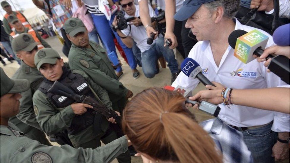Handout photo released by the Colombian presidential press office showing Colombian President Juan Manuel Santos (right) shaking hands with a member of Venezuelan National Guard in Paraguachon on 15 September, 2015.