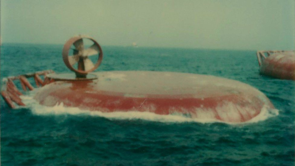 A large red metal dome floats in the sea