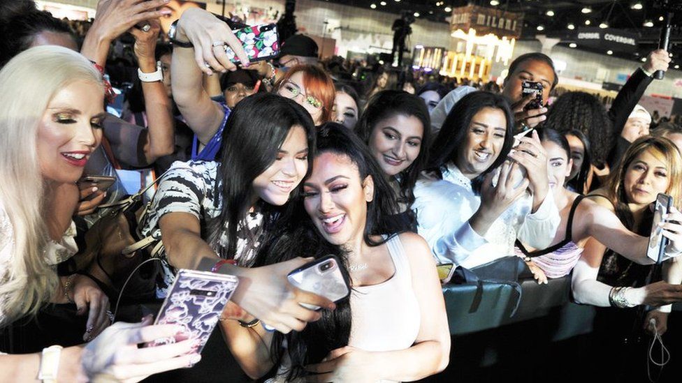 Beauty influencer Huda Kattan poses with fans at BeautyCon