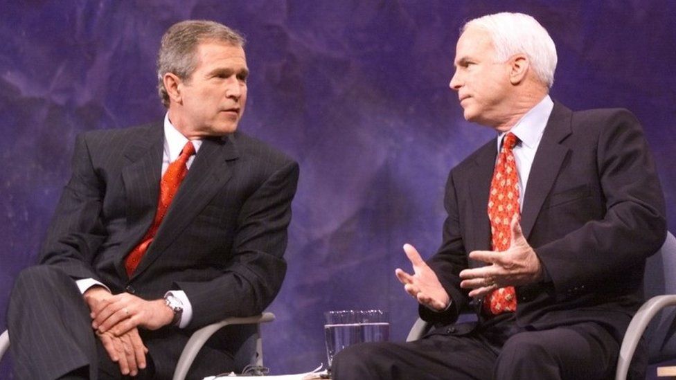Republican US presidential candidates Texas Governor George W. Bush (L) and Senator John McCain of Arizona talk before the start of the Iowa debate