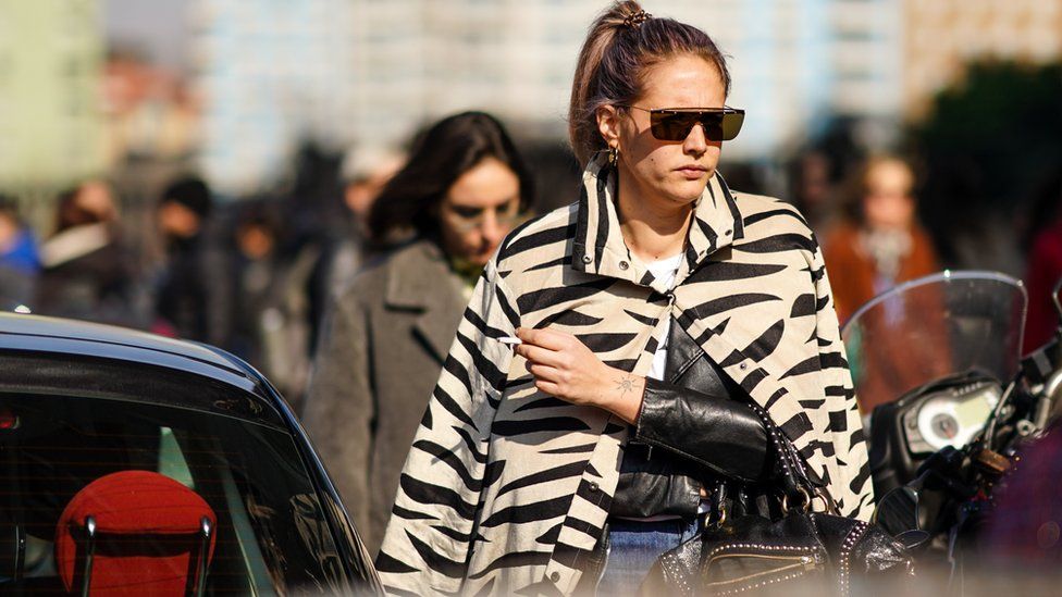 Гость носит серьги, солнцезащитные очки, бежево-черную куртку с рисунком зебры, черную кожаную куртку вне MSGM во время Недели моды в Милане осень / зима 2020-2021, 22 февраля 2020 г.