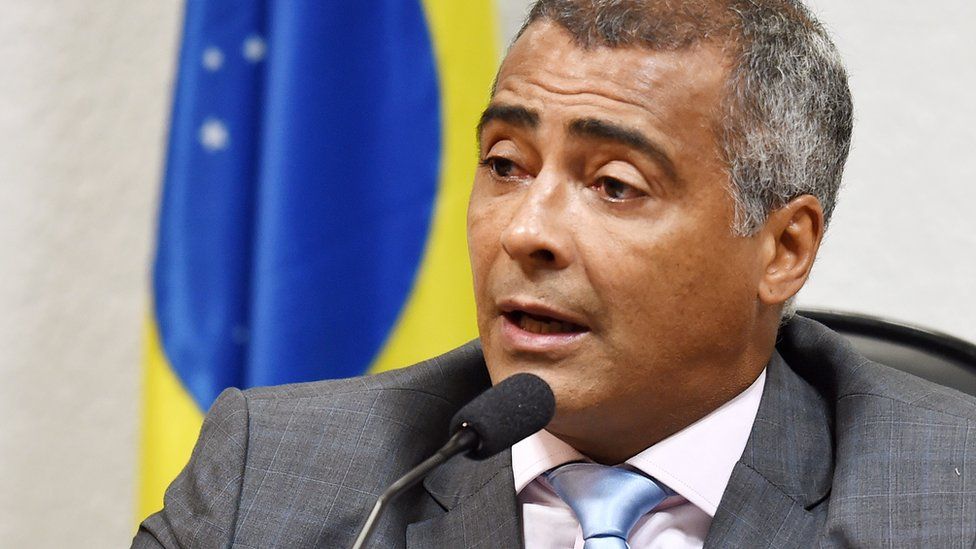 Romario pictured at microphone in front of flag at 2015 event