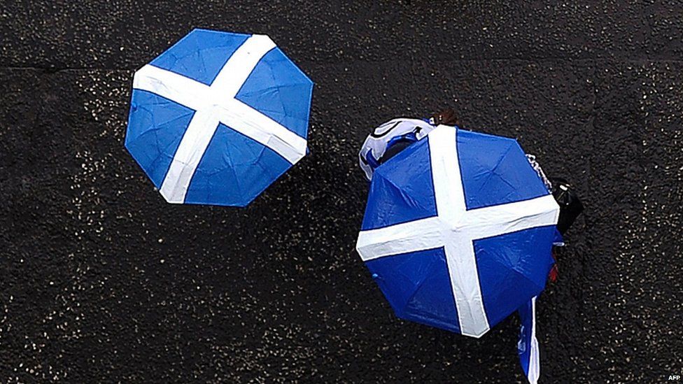 Scottish independence campaigners holding umbrellas in the pattern of the Saltire flag