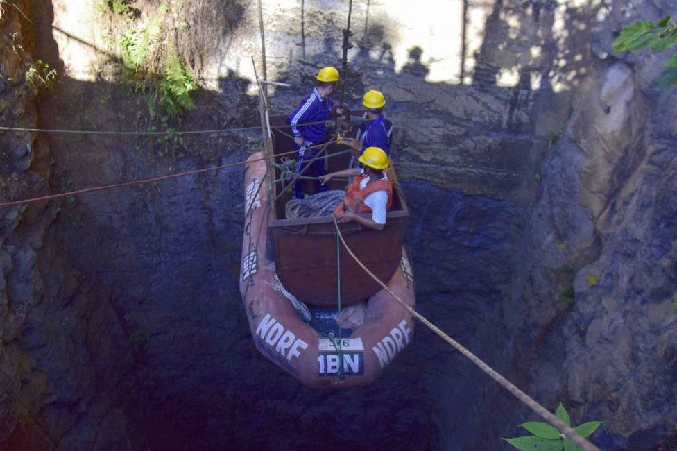 Indian navy divers go down into the mine with a pulley during rescue operations.