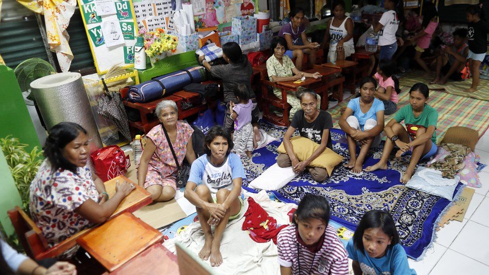 Filipino villagers rest inside a school turned into a temporary shelter in the town of Aparri
