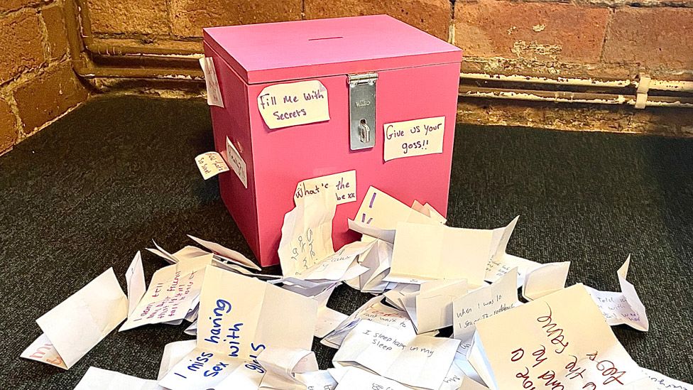 Коробка, в которой хранились секреты, рядом с кучей листков бумаги с написанными на них секретами
