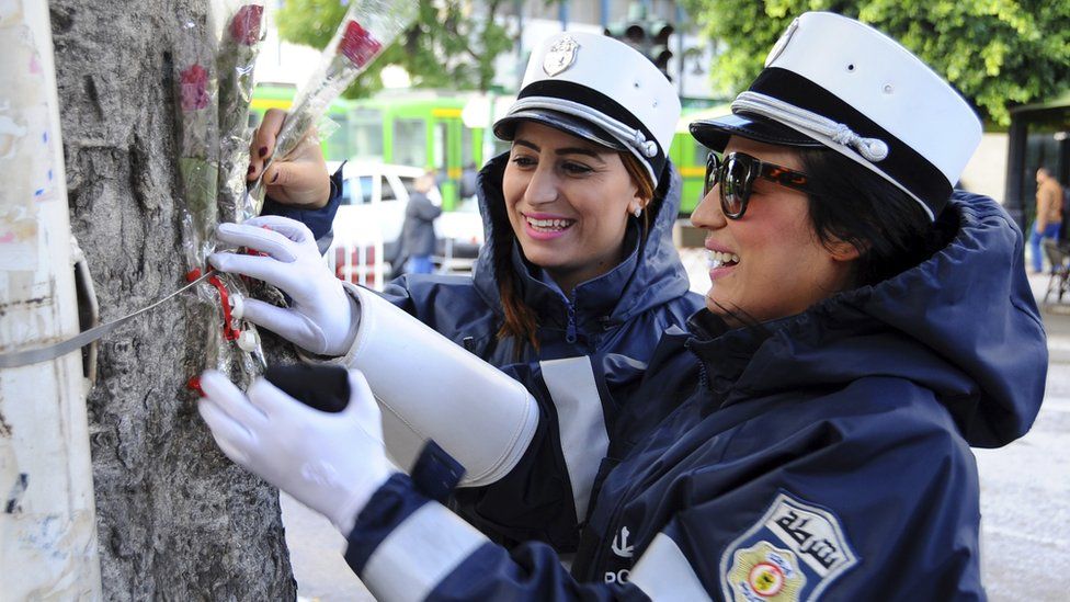 Police officers place roses onto a tree in downtown Tunis, Thursday, Nov. 26, 2015. Tunisian authorities have identified a suicide bomber who targeted presidential guards in a deadly attack, saying he was a 27-year-old local street vendor. The Islamic State group claimed responsibility for Tuesday"s attack on a bus in central Tunis, which left 12 dead plus the attacker.