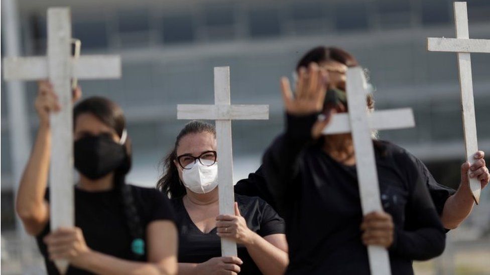 Демонстранты держат кресты во время акции протеста, посвященной 600 000 смертей от COVID-19 в Бразилии и борьбе президента Бразилии Жаира Болсонару с пандемией коронавируса, в Бразилиа, Бразилия, 8 октября 2021 г.