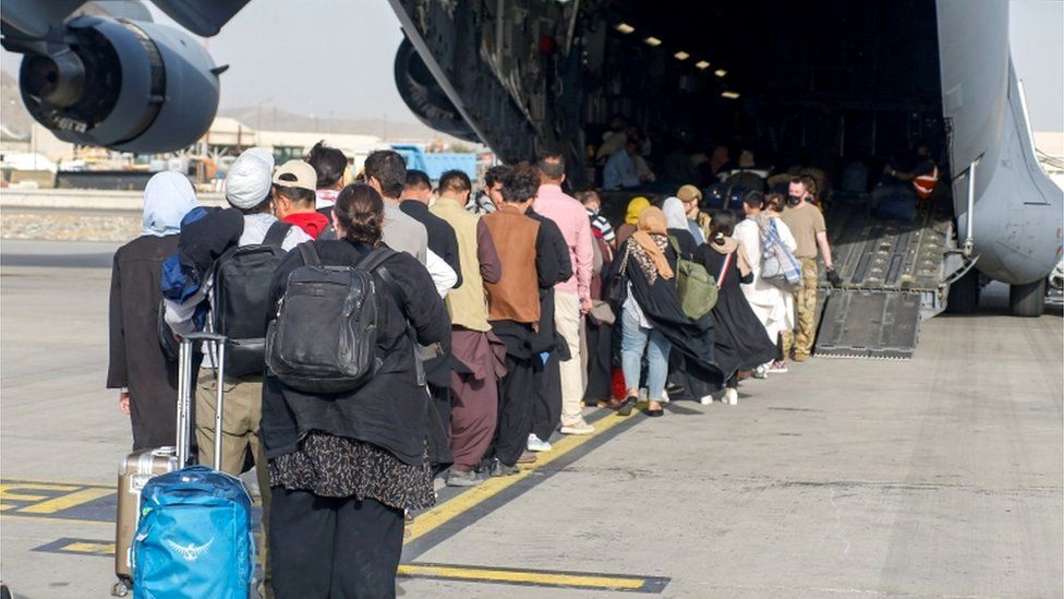People queue to board a US transport plane at Kabul international airport