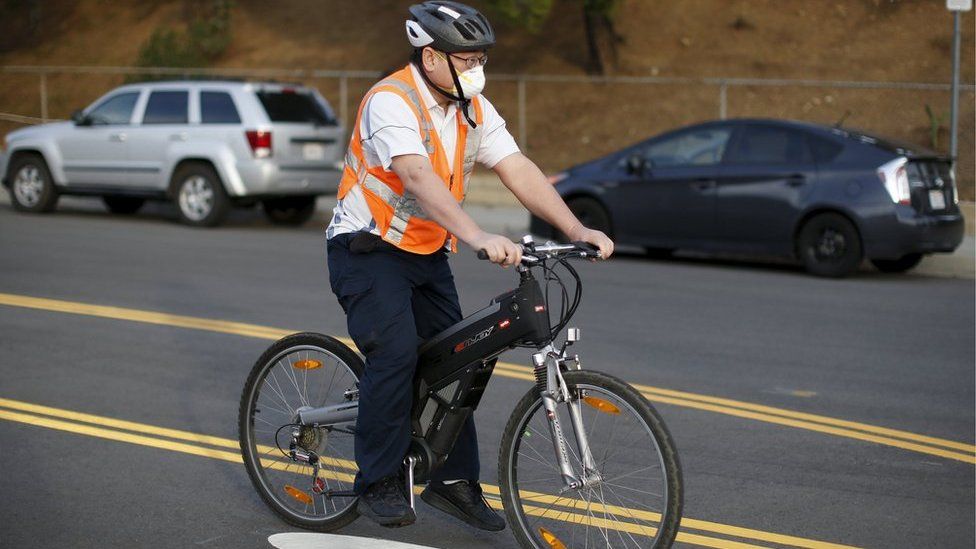 A man cycles wearing a face mask near the site of the Aliso Canyon storage field where gas has been leaking in Porter Ranch