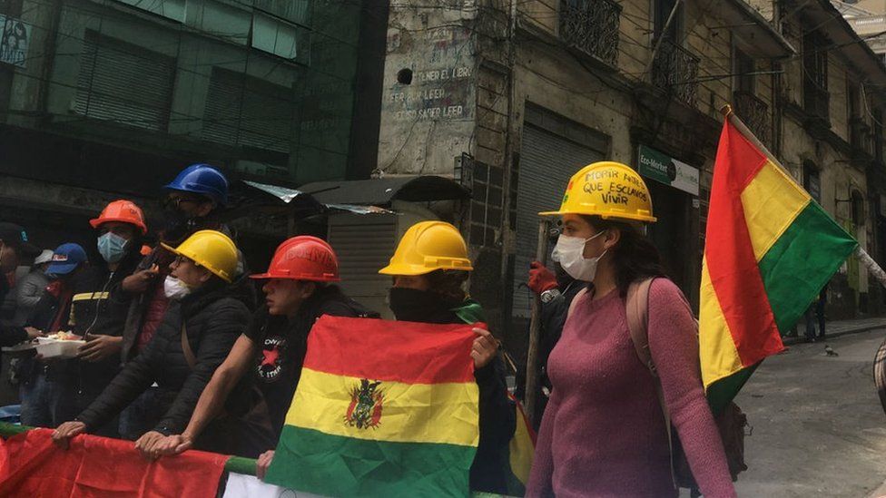 A group of protesters wearing hard hats man a barricade near Mr Morales' home and office