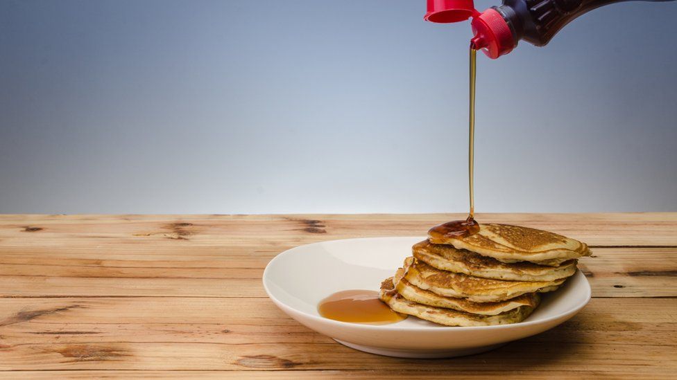Maple syrup being poured onto pancakes