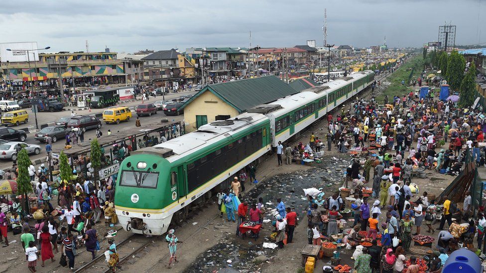 A stationery train in Nigeria surrounded by crowds of people