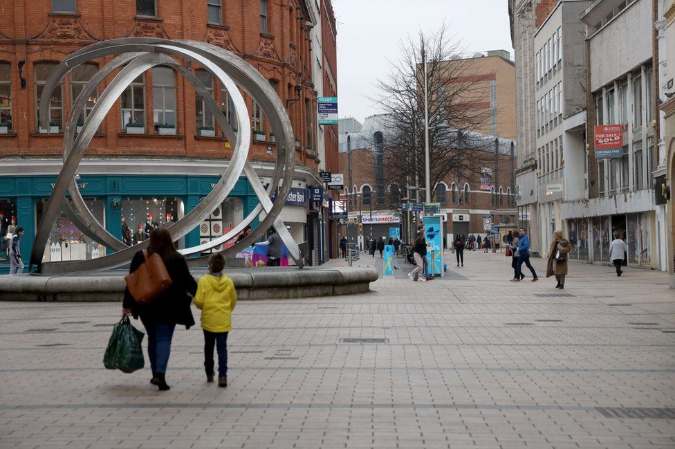 A small number of people on a shopping street in Belfast city centre