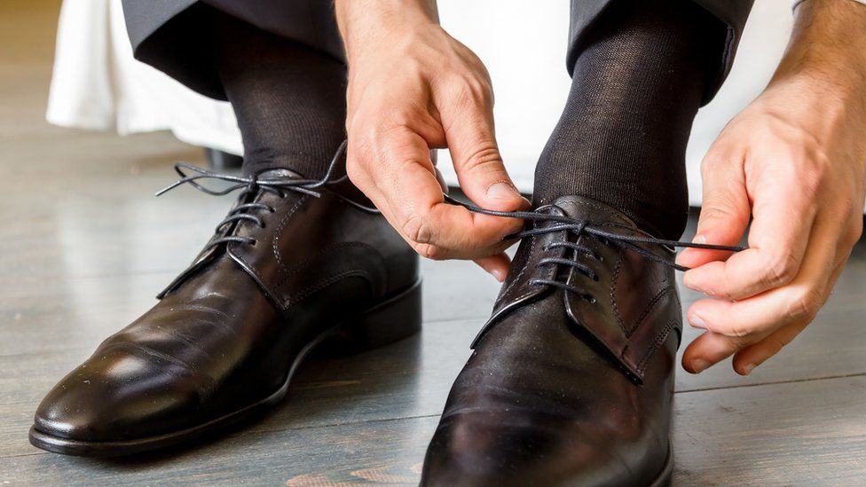 A stock image of a man doing his shoe laces