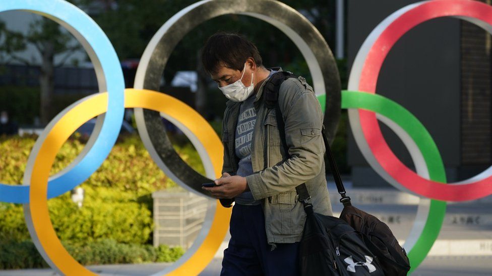 A passerby walks past an Olympic Rings monument displayed near the National Stadium, the main venue of the Tokyo 2020 Olympics and Paralympics, in Tokyo, Japan,