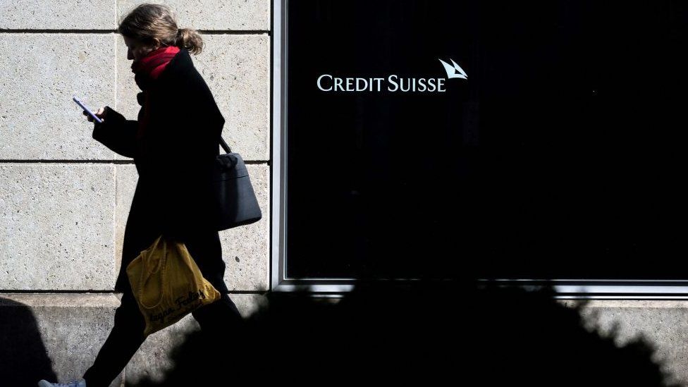 Woman walking past Credit Suisse bank