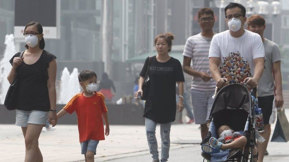 A family wearing masks walk at the haze-shrouded shopping district of Orchard Road in Singapore September 24, 2015.