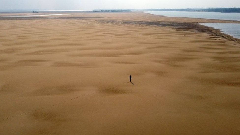 In this aerial view environmentalist Luis Martinez walks along a sand bank at the Parana River, during a historic drought, near Paso de la Patria, Corrientes, Argentina, on August 20, 2021.