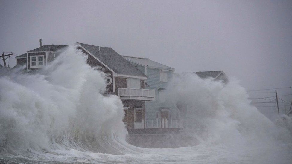 Waves crash over oceanfront homes during a noreaster in Scituate, Massachusetts on January 29, 2022. - Blinding snow whipped up by near-hurricane force winds pummeled the eastern United States