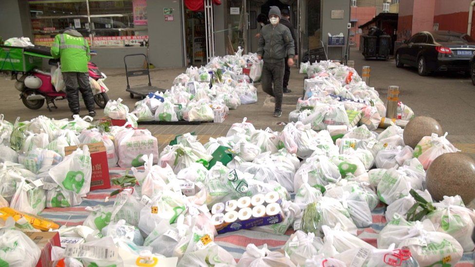 Piles of groceries are placed on the ground outside a Beijing shop awaiting delivery riders