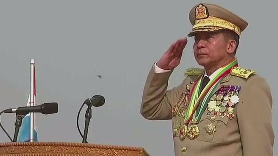 Генерал Мин Аун Хлаинг стоит на трибуне и отдает честь