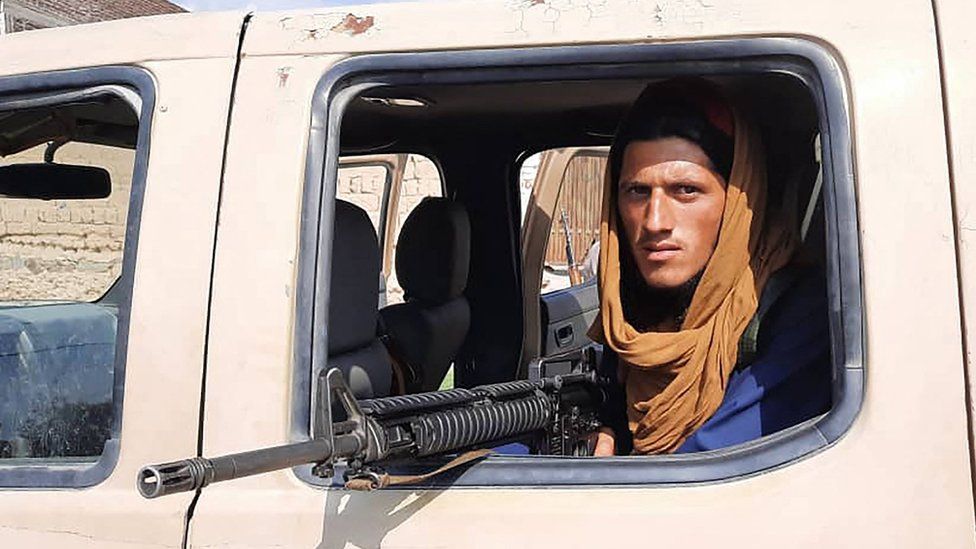 A Taliban fighter sits inside an Afghan National Army (ANA) vehicle along the roadside in Laghman province on August 15, 2021