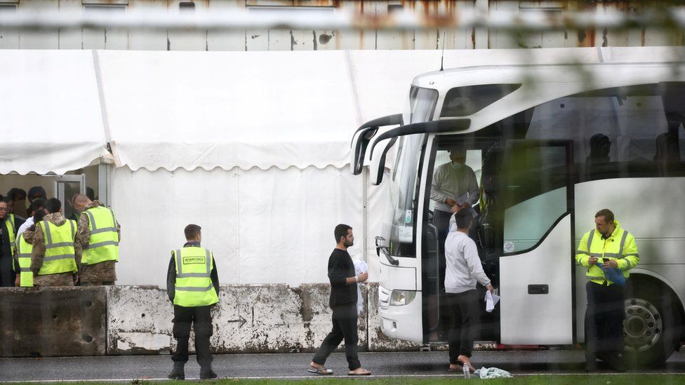 People board a bus at the migrant processing centre in Manston