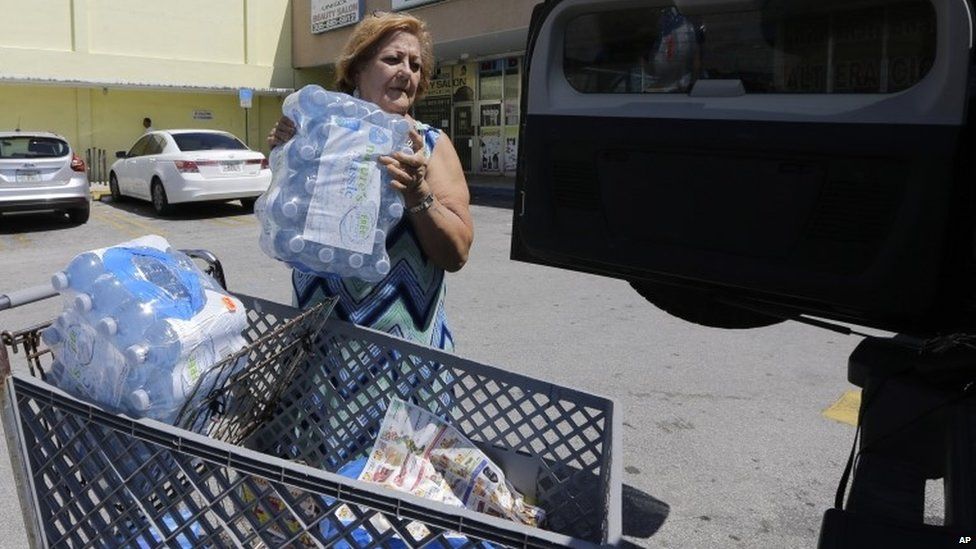 Rosa Monzon loads water bottles into her car as she prepares for Tropical Storm Erika