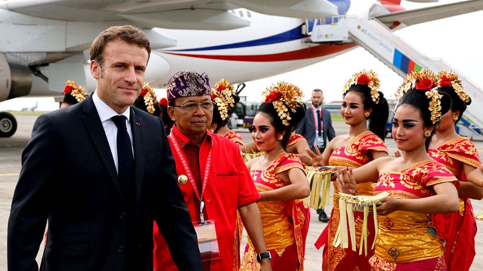 French President Emmanuel Macron is welcomed as he arrives before the G20 Summit, at Ngurah Rai International airport in Denpasar on the Indonesian resort island of Bali on 14 November 2022