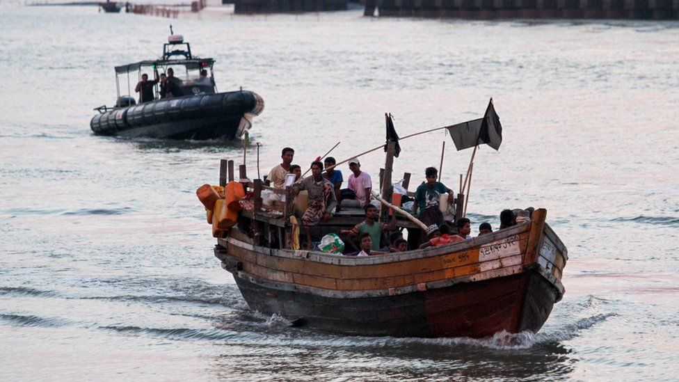 A wooden boat carrying Rohingya refugees including many children being detained by the authorities off the coast of Malaysia