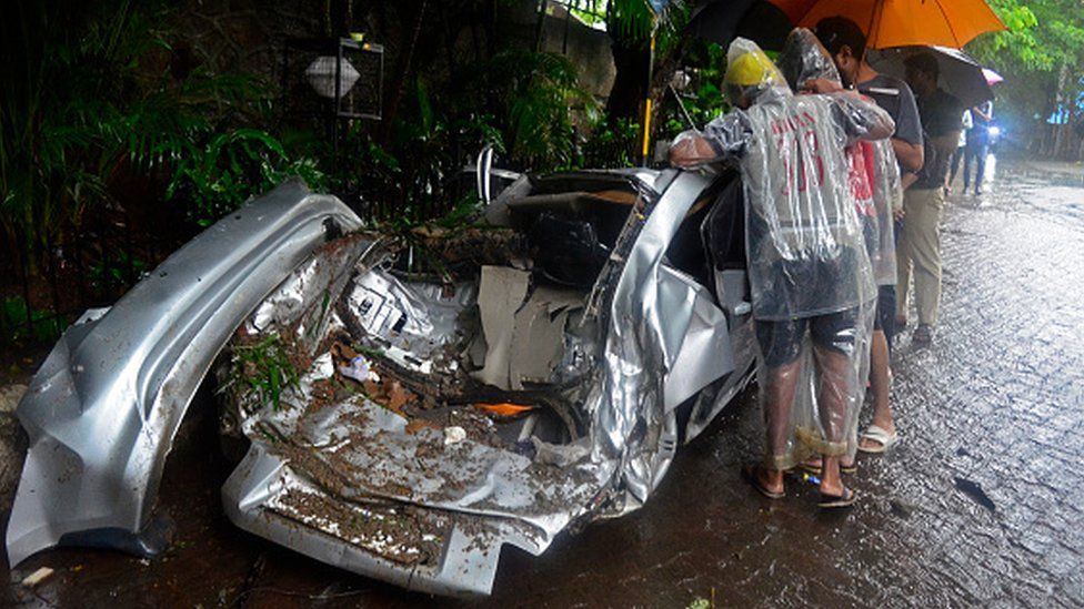 Мужчина заглядывает в машину, поврежденную после обрушения стены во время проливных дождей в Мумбаи, Индия, 05 Июль 2022 г.