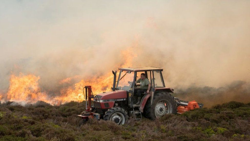A farmer attempts to create a firebreak through heather and gorse as a wildfire rages across the hills of the Clwydian Range, above the village of Rhewl, Llangollen, on June 1, 2021