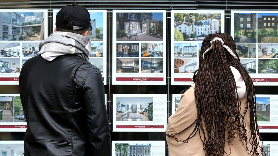 People looking at estate agent window in London