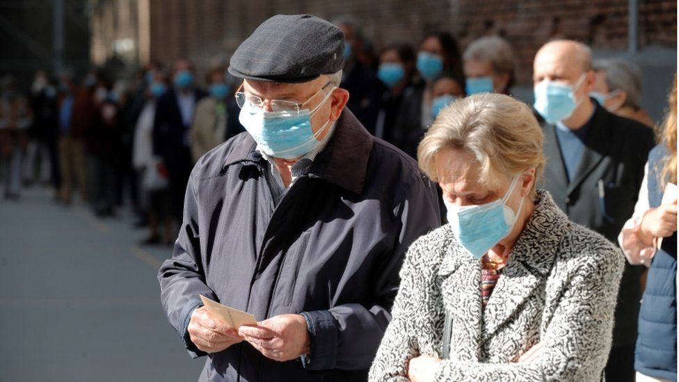 Voters wait in a queue outside a polling station during Madrid's regional election