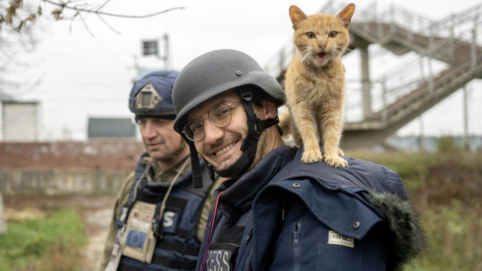 Soldin smiles to the camera as a cat stands on his shoulders during an assignment for AFP in Ukraine