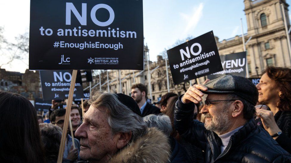 protestors holding signs reading "no to antisemitism #enoughisenough"