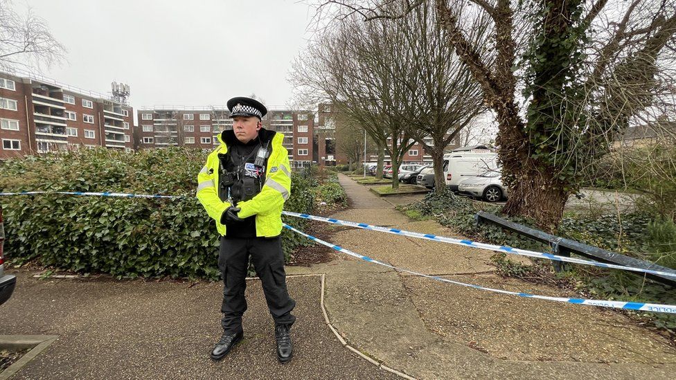 Police officer standing at cordon near the Ferrars Way/Carlton Way junction in Cambridge