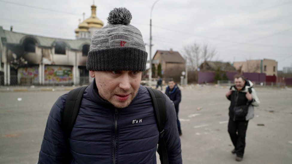 Andrei is a man in his 30s, pictured wearing a backpack and a bobble hat as he left the town of Irpin