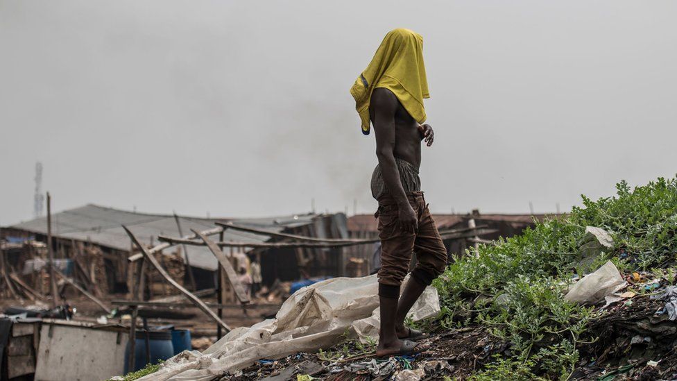 A man stands on a heap of wood shavings in Lagos