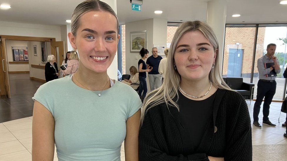 Two girls smiling as they receive their A-level results.