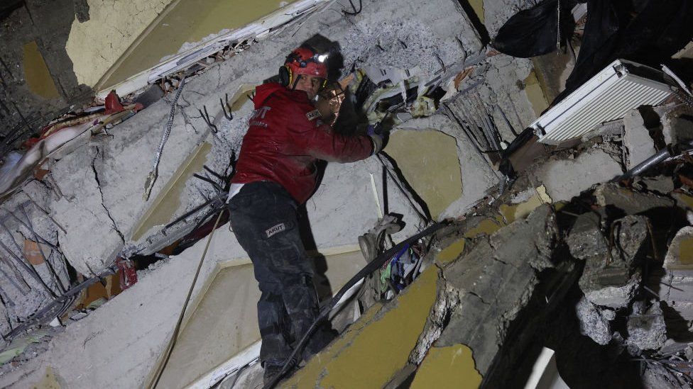 Спасатель ищет пострадавших и выживших среди обломков разрушенных зданий в Кахраманмараше, Турция