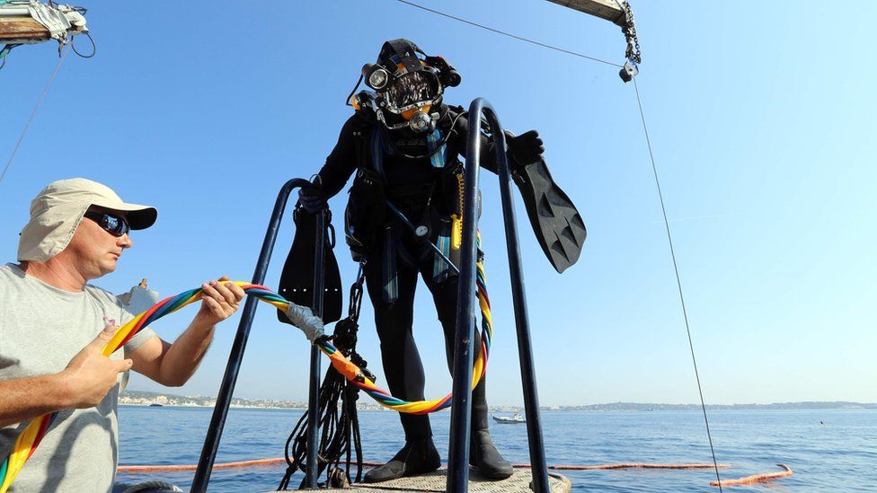 A diver in full gear, about to enter the sea from a boat