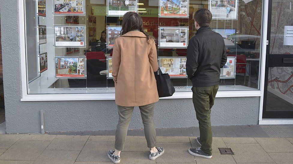 Young people looking in an estate agents' window